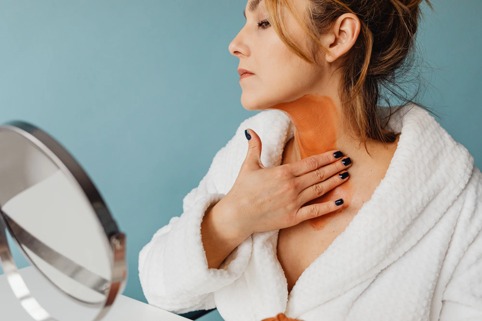 Mujer madura de perfil con una mascarilla hidratante sobre el cuello y el escote