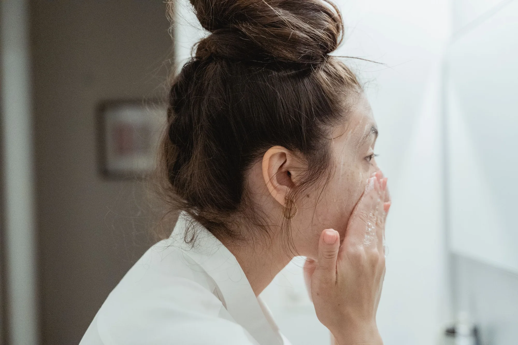 Mujer aplica un producto suave en su rostro como parte de los cuidados después de la radiofrecuencia facial